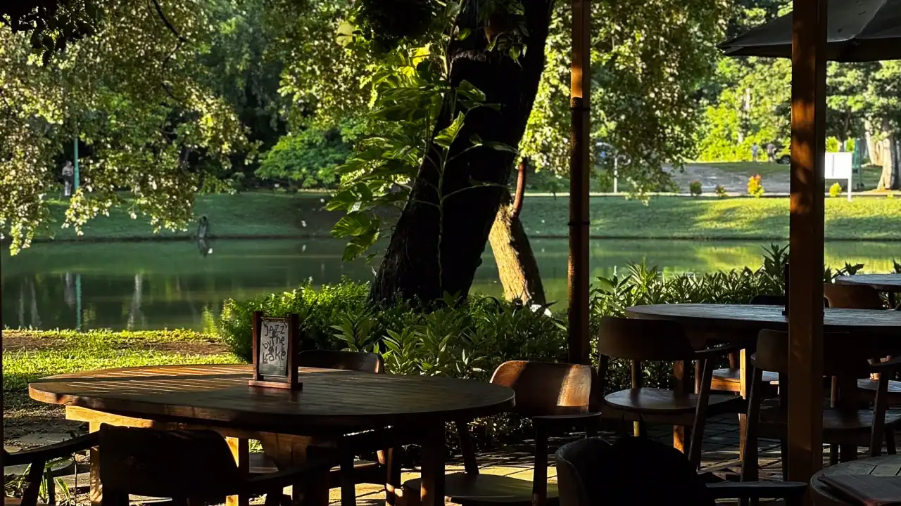 Meja kayu di bawah kanopi Banyoo, menghadap danau dan pepohonan