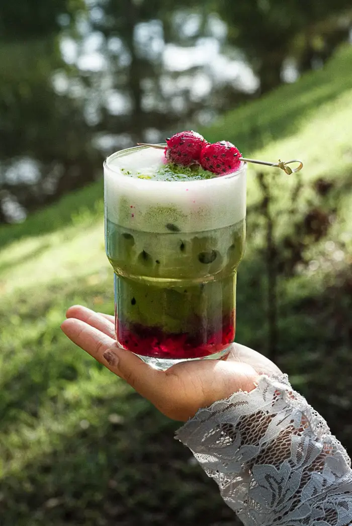 A layered matcha drink held in one hand