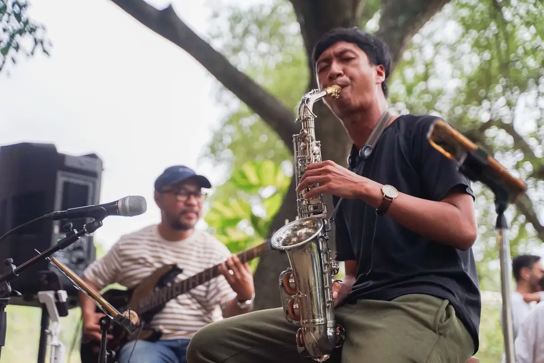 Band tampil di bawah pepohonan di Banyoo, dengan saksofon